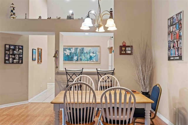 dining space with light wood-type flooring and an inviting chandelier