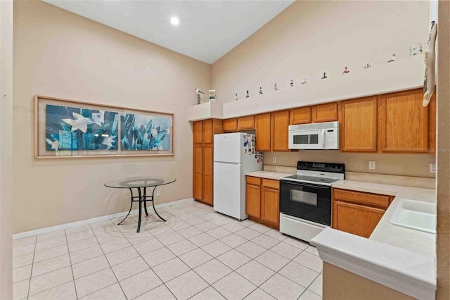 kitchen with light tile patterned floors, white appliances, and sink