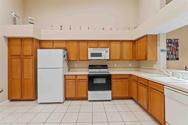 kitchen with white appliances, sink, light tile patterned floors, and a high ceiling