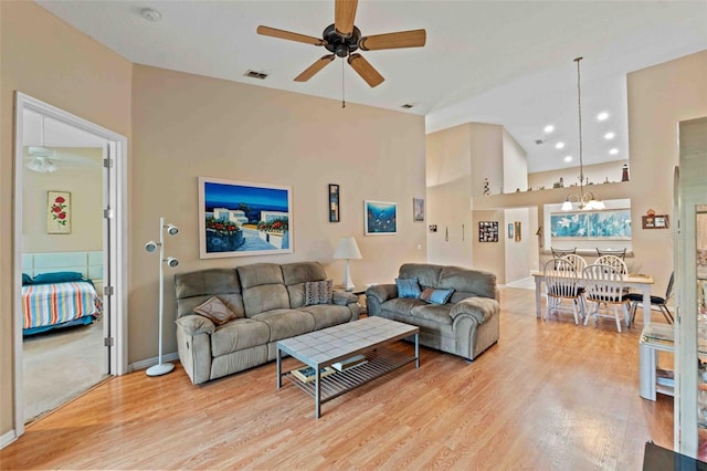 living room with ceiling fan with notable chandelier, light hardwood / wood-style flooring, and lofted ceiling