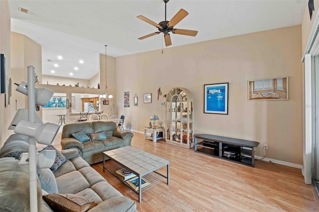 living room with a high ceiling, light hardwood / wood-style flooring, and ceiling fan