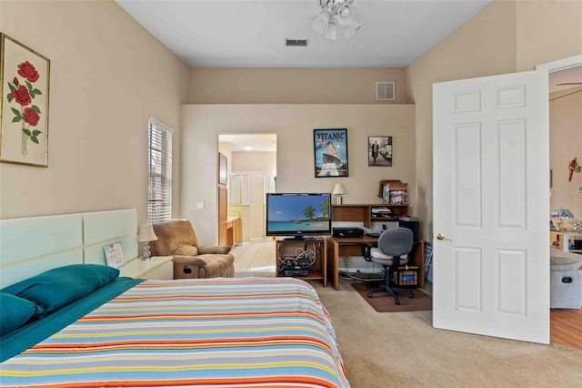 bedroom with ensuite bath and light colored carpet