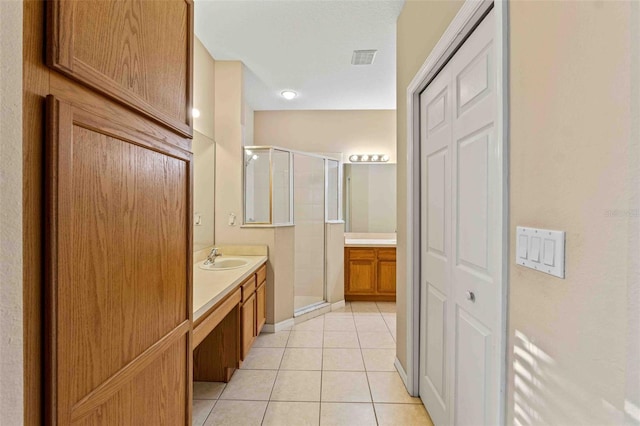 bathroom featuring tile patterned flooring, vanity, and a shower with shower door