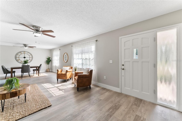 foyer entrance featuring ceiling fan, a textured ceiling, and light wood-type flooring