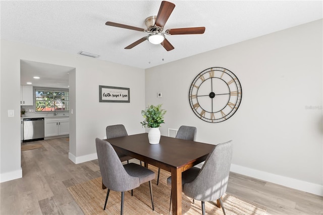 dining area featuring ceiling fan, sink, a textured ceiling, and light wood-type flooring