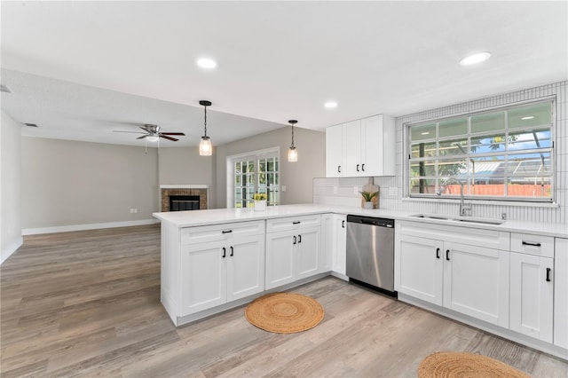 kitchen featuring white cabinetry, sink, stainless steel dishwasher, kitchen peninsula, and decorative light fixtures