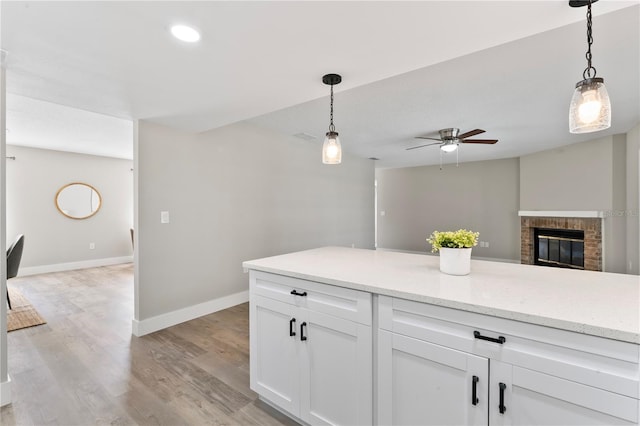 kitchen featuring ceiling fan, light hardwood / wood-style floors, white cabinetry, and hanging light fixtures