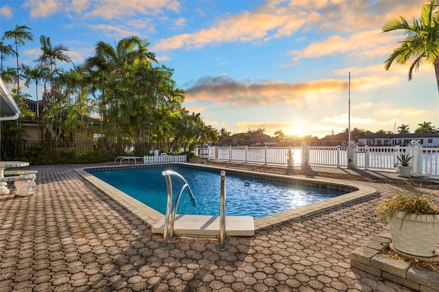 pool at dusk with a patio area