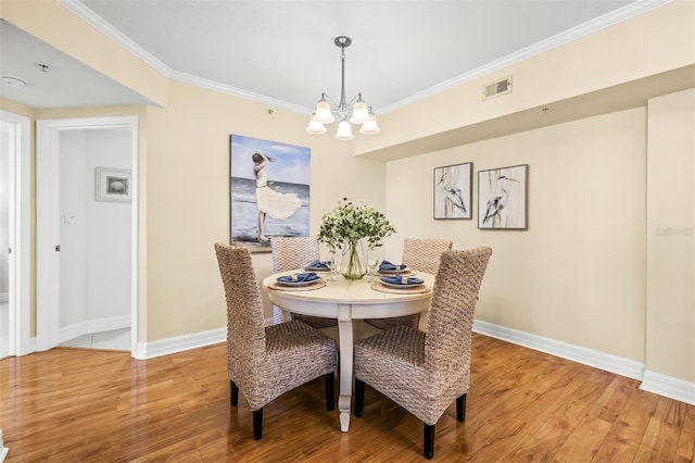 dining area with hardwood / wood-style flooring, crown molding, and a notable chandelier