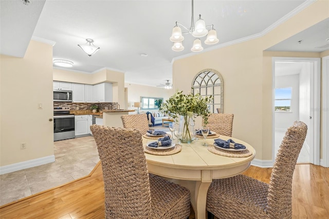 dining space featuring ceiling fan with notable chandelier, light wood-type flooring, and ornamental molding