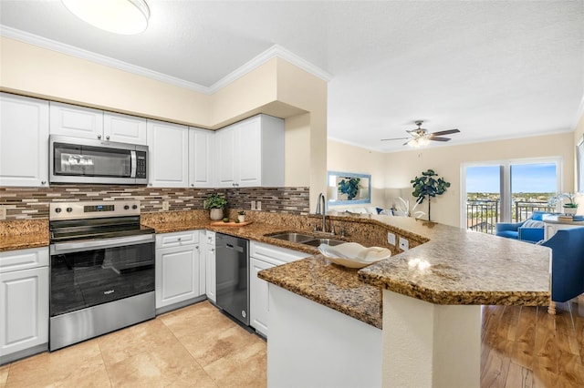 kitchen featuring ceiling fan, stainless steel appliances, kitchen peninsula, crown molding, and white cabinets