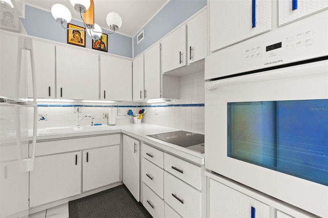 kitchen featuring white cabinetry, sink, oven, black electric cooktop, and decorative backsplash