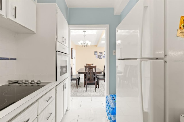 kitchen featuring pendant lighting, white appliances, white cabinetry, and an inviting chandelier