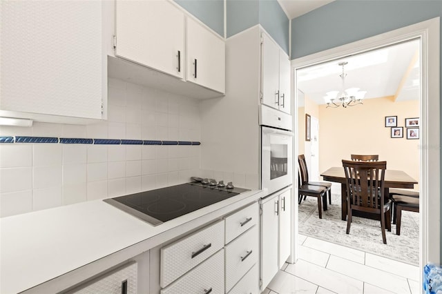 kitchen with white cabinetry, a notable chandelier, oven, decorative light fixtures, and black electric stovetop