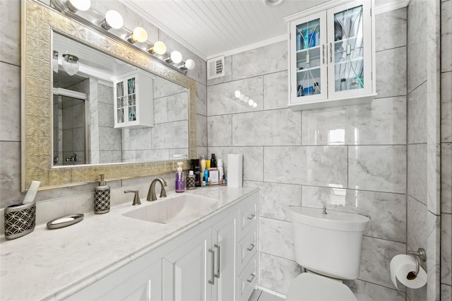 bathroom featuring vanity, toilet, tile walls, and crown molding