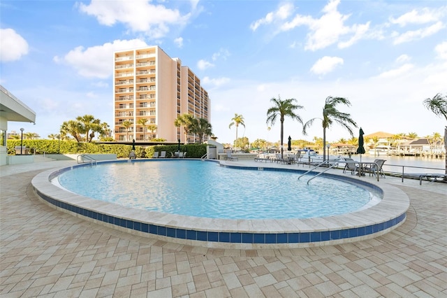 view of pool with a water view and a patio