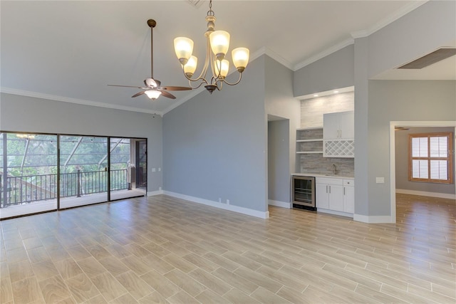 unfurnished living room with high vaulted ceiling, ceiling fan with notable chandelier, wine cooler, light hardwood / wood-style flooring, and ornamental molding