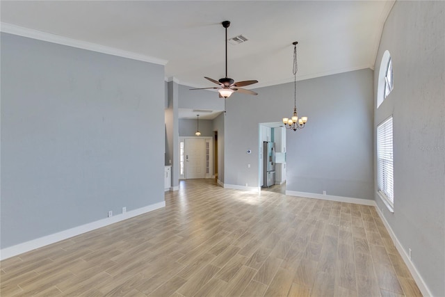 unfurnished living room with ceiling fan with notable chandelier, a towering ceiling, light wood-type flooring, and crown molding