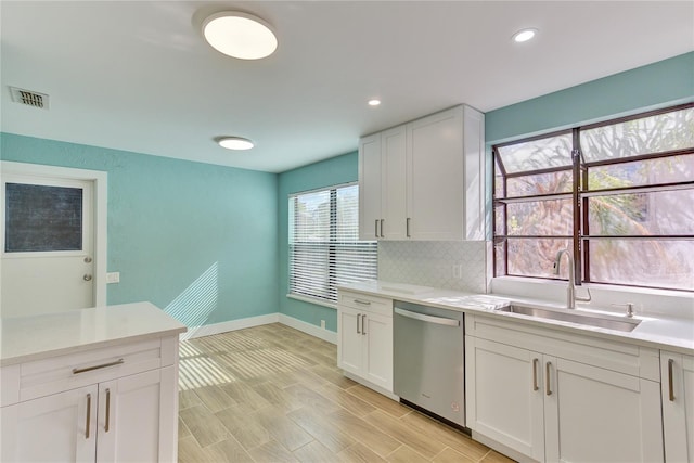 kitchen with white cabinets, light wood-type flooring, stainless steel dishwasher, and sink