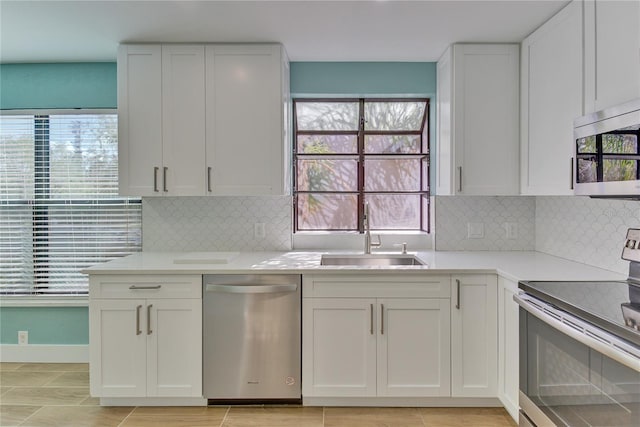 kitchen with white cabinets, appliances with stainless steel finishes, backsplash, and sink