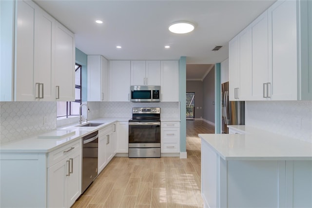 kitchen featuring white cabinets, sink, crown molding, decorative backsplash, and stainless steel appliances