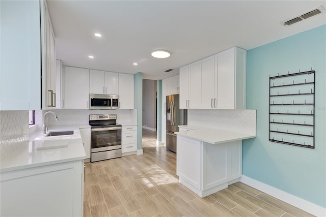 kitchen featuring white cabinetry, sink, stainless steel appliances, and light hardwood / wood-style flooring