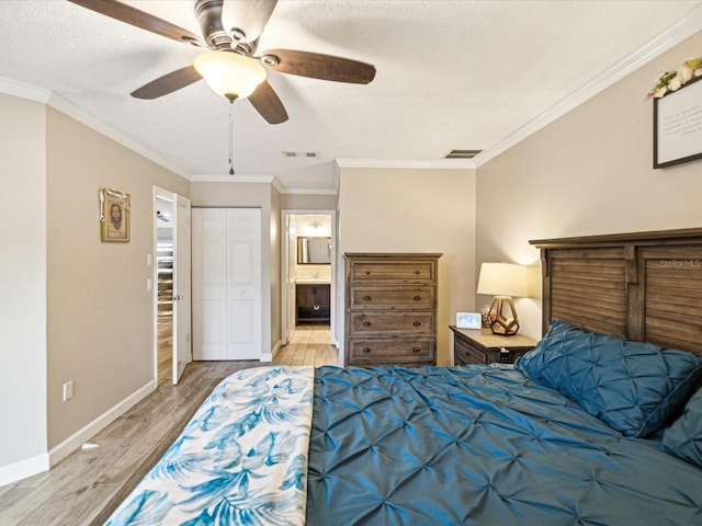 bedroom featuring ceiling fan, crown molding, light hardwood / wood-style flooring, and ensuite bath