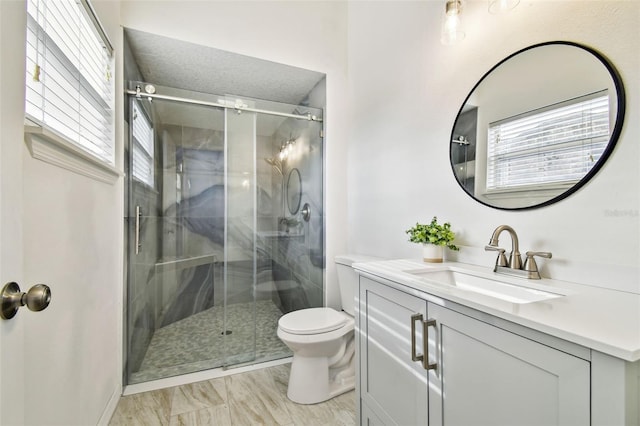 bathroom with vanity, a healthy amount of sunlight, an enclosed shower, and toilet