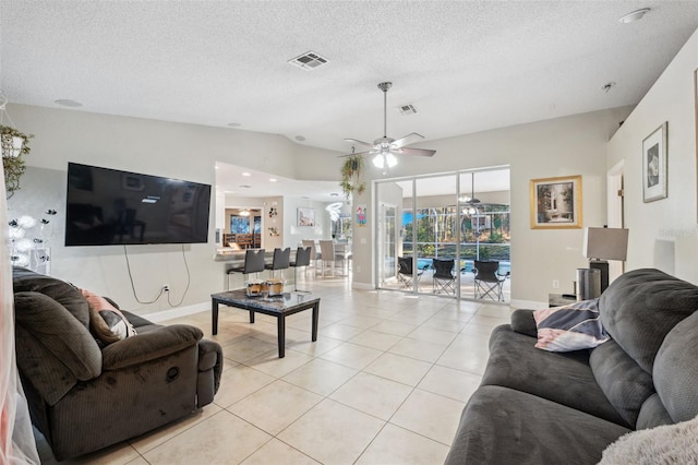 living room with ceiling fan, lofted ceiling, a textured ceiling, and light tile patterned floors