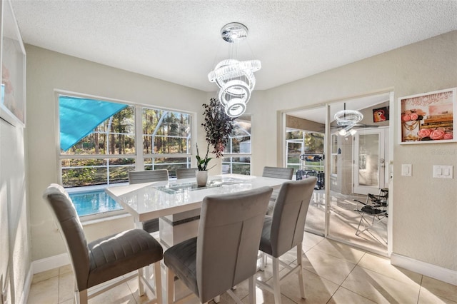 tiled dining room featuring a textured ceiling, a healthy amount of sunlight, and a notable chandelier