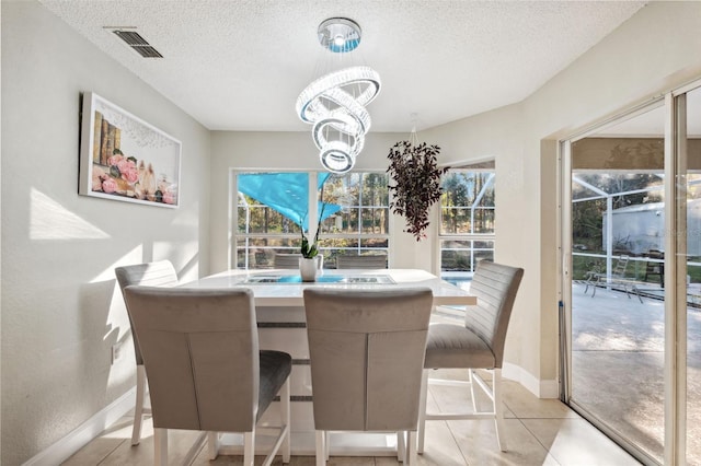 tiled dining space with a textured ceiling and a notable chandelier