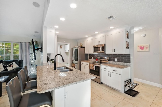 kitchen featuring light stone countertops, sink, white cabinets, and stainless steel appliances