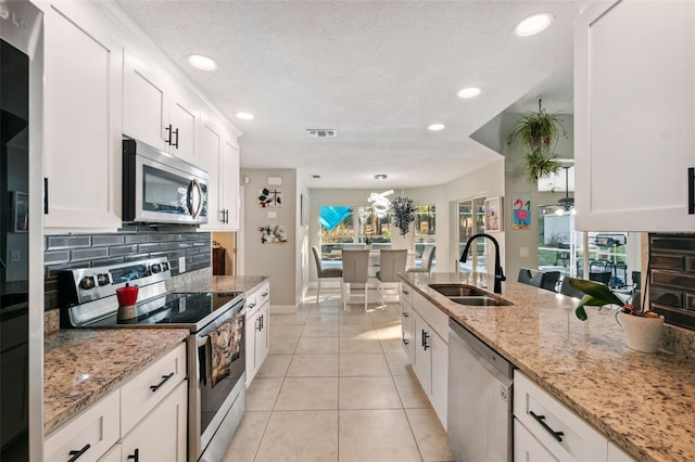 kitchen featuring light stone countertops, sink, stainless steel appliances, white cabinets, and light tile patterned flooring