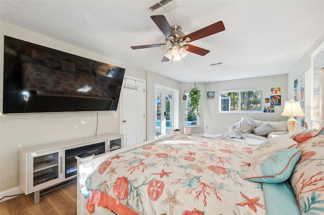 bedroom with french doors, a textured ceiling, access to outside, ceiling fan, and hardwood / wood-style flooring