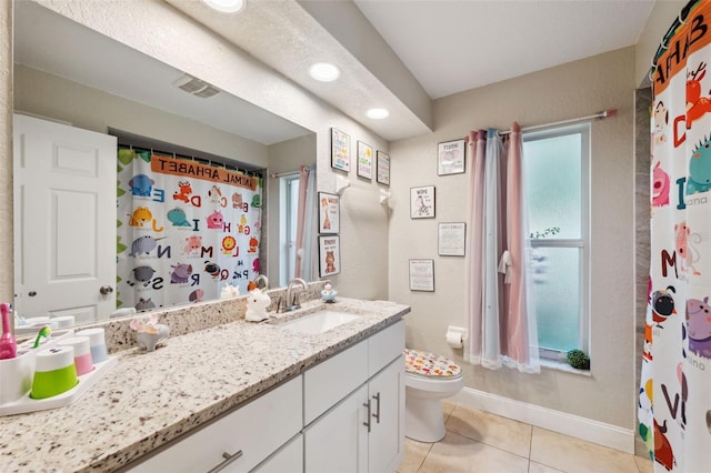 bathroom with tile patterned flooring, vanity, toilet, and a wealth of natural light