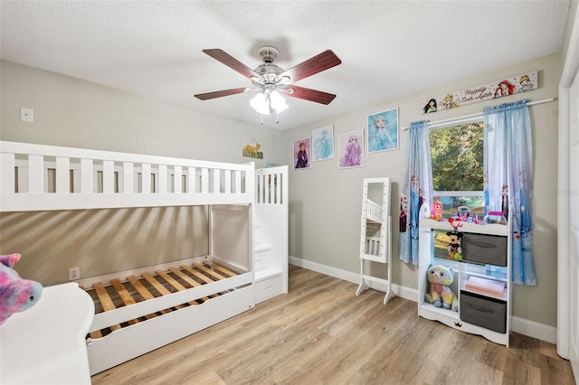 bedroom with ceiling fan, a textured ceiling, and light wood-type flooring