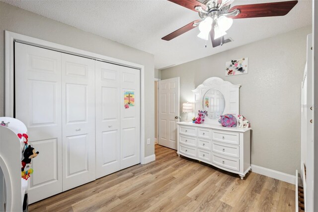 bedroom featuring a textured ceiling, light wood-type flooring, a closet, and ceiling fan