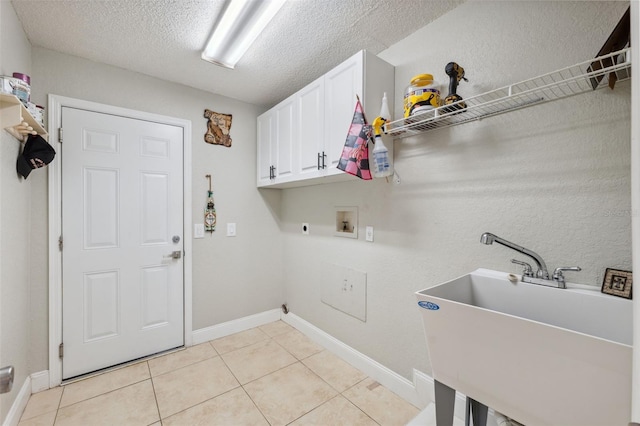 laundry area featuring electric dryer hookup, cabinets, sink, washer hookup, and light tile patterned floors