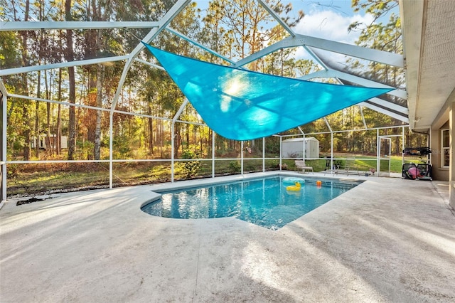 view of swimming pool with a patio, glass enclosure, and a shed