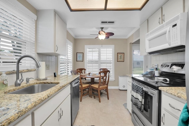 kitchen featuring decorative backsplash, appliances with stainless steel finishes, light stone countertops, sink, and white cabinetry