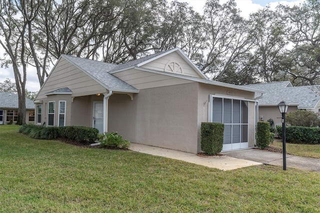 view of front facade featuring a shingled roof, a front yard, and stucco siding