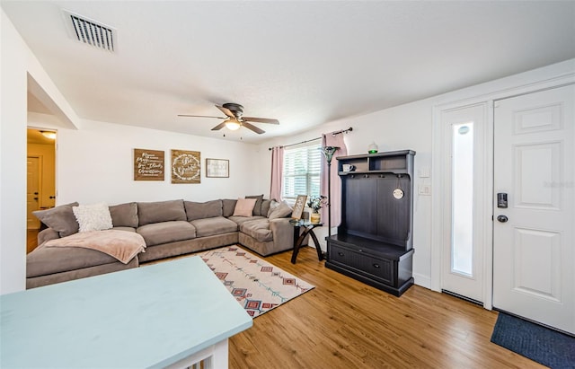 living area featuring light wood-style flooring, a ceiling fan, and visible vents