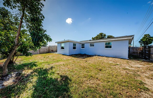 rear view of house featuring a lawn and a fenced backyard