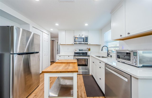 kitchen with a toaster, light wood-style flooring, stainless steel appliances, wood counters, and a sink