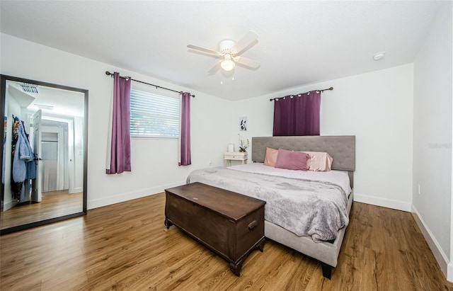 bedroom featuring visible vents, baseboards, wood finished floors, and a ceiling fan