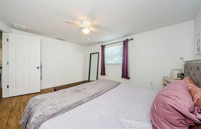 bedroom with baseboards, wood finished floors, visible vents, and ceiling fan