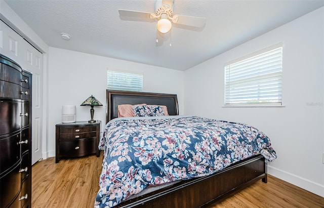 bedroom featuring a textured ceiling, baseboards, light wood-style floors, and a ceiling fan