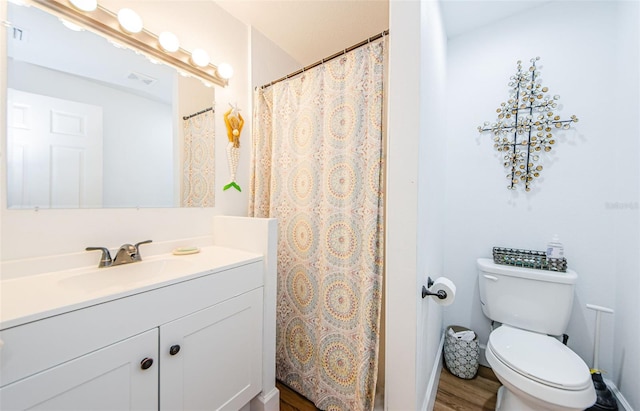 full bath featuring visible vents, toilet, vanity, and wood finished floors