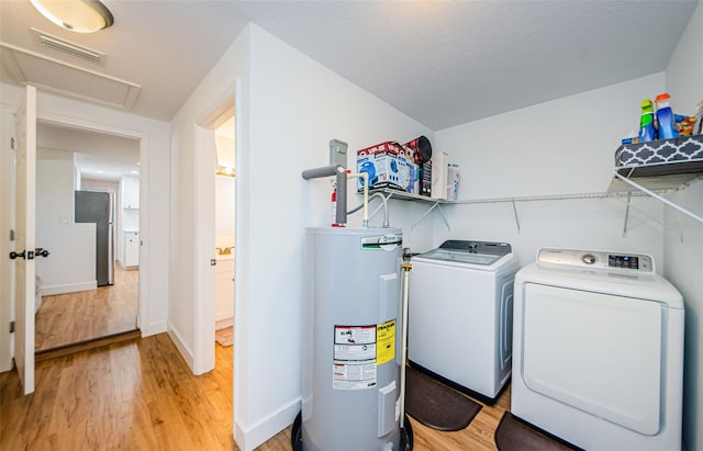 laundry room featuring visible vents, electric water heater, light wood-style flooring, and laundry area