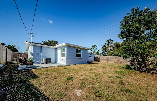 rear view of property featuring central air condition unit, a patio, a yard, and a fenced backyard